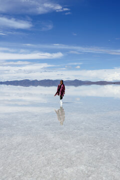 Young asian woman walking on the mirror of the Salar de Uyuni, Bolivia