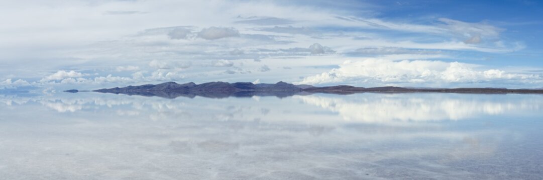 Panoramic reflection of clouds and mountain on the Salar de Uyuni, Bolivia