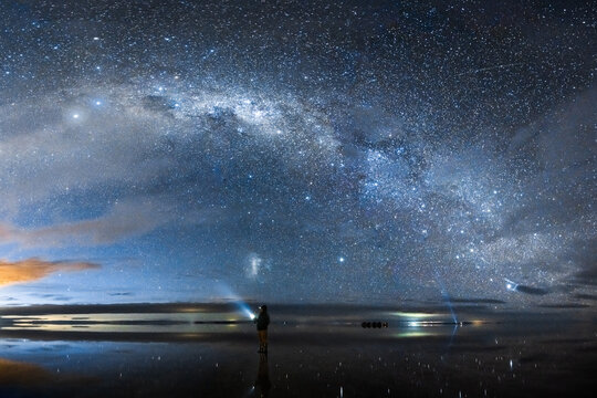 Man with flashlight and Milky Way over the Salar de Uyuni at night, Bolivia