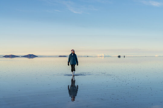 Asian woman walking on the flooded Salar de Uyuni, Bolivia