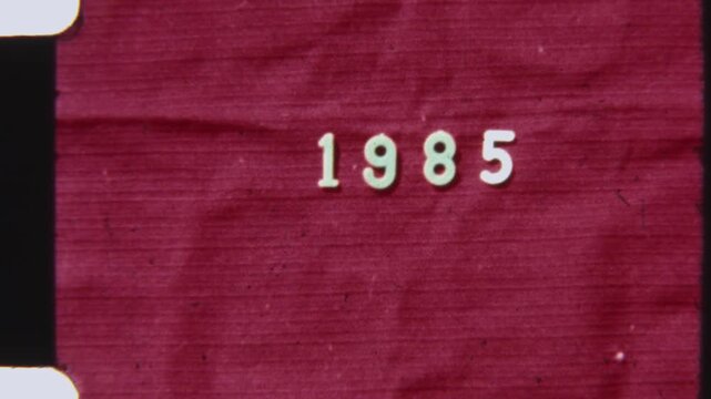 1985 Text on Vintage Red Background with Flickering 8mm Film Effect
