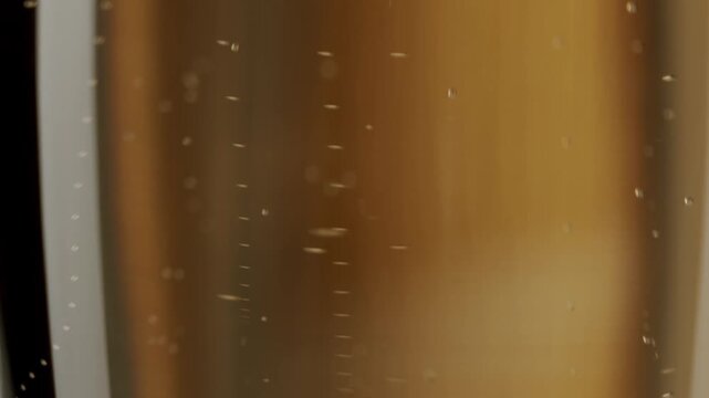 Effervescent golden liquid fizzing in slow motion, representing celebration, luxury and success. close-up of golden champagne with effervescent bubbles rising to the surface in a continuous flow,