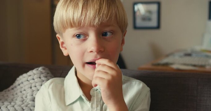 Young boy pulling out his own loose baby tooth with a string