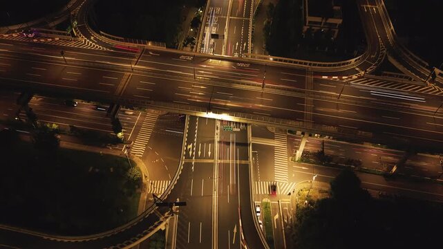 Aerial view of a city highway interchange at night with moving cars and bright lights