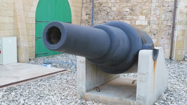 coastal defense gun fort st elmo rifled muzzle loader cannon green door limestone wall gravel yard valletta malta historic weaponry artillery exhibit coastal defense artillery display collection
