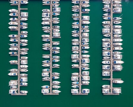 Aerial top-down view of luxury yachts and boats moored in neat rows at a marina