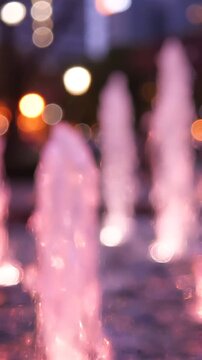 Mesmerizing Water Fountains: A Captivating Display of Colorful Jets and Bokeh Lights Set Against a Delightful City Evening Ambiance