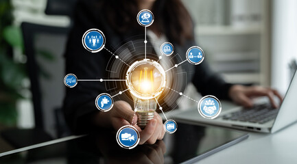 A businesswoman holds a light bulb symbolizing innovation, surrounded by icons representing ideas and connections, highlighting creativity in a modern workspace. Crux © InfiniteFlow