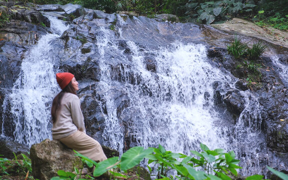 Blurred of a woman sitting and relaxing by the waterfall in the forest