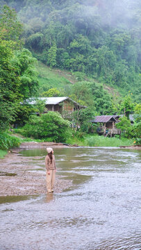 A woman standing by the river in rural village and looking at a beautiful nature
