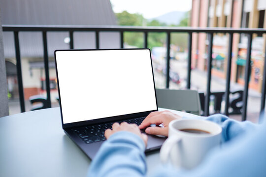 Mockup image of a woman working and typing on laptop computer with blank white desktop screen in cafe