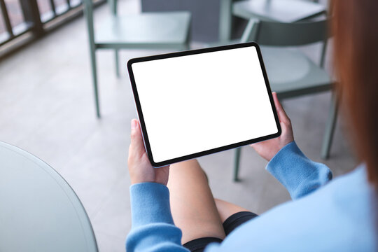 Mockup image of a woman holding digital tablet with blank white desktop screen in cafe