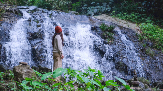 Rear view of a woman looking at the waterfall in the forest