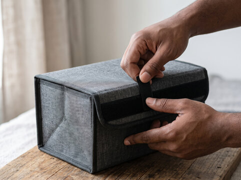 Person closing reusable fabric shipping box with velcro flap seal