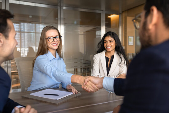 Multiethnic businesspeople handshake, confirming partnership or agreement during negotiations, corporate meeting at conference table in office boardroom. Business cooperation, sealing commercial deal