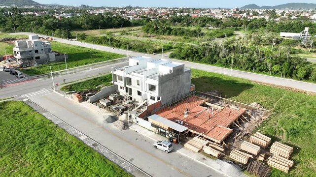 Aerial view of a construction site with workers building a modern house using pre-cast concrete structures in Florianopolis, Santa Catarina, Brazil.
