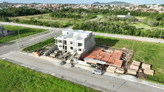 Aerial view of a construction site with workers building a modern house using pre-cast concrete structures in Florianopolis, Santa Catarina, Brazil.