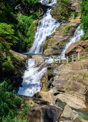 Ravana Falls cascades over rugged rock formations amid lush tropical vegetation near Ella, Sri Lanka. A scenic natural landmark in the central highlands © nilanka