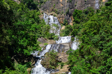 Ravana Falls, also known as Ravana Ella, cascades over rugged rock formations amid lush tropical vegetation near Ella, Sri Lanka. Scenic natural landmark in the central highlands © nilanka