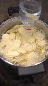 Cooking Thai pork ribs soup with bamboo shoots on charcoal stove. Simmering pork ribs in broth, adding blanched sliced bamboo shoots, and pounding garlic chili dip in mortar to serve with hot clear so