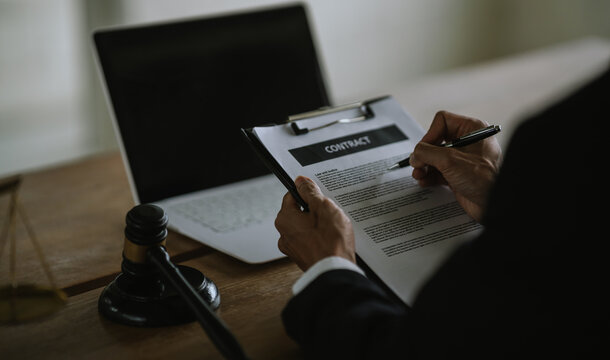 Lawyer reviewing legal documents with a laptop, gavel, and scales of justice, representing legal services, law practice, justice, and professional consultation.