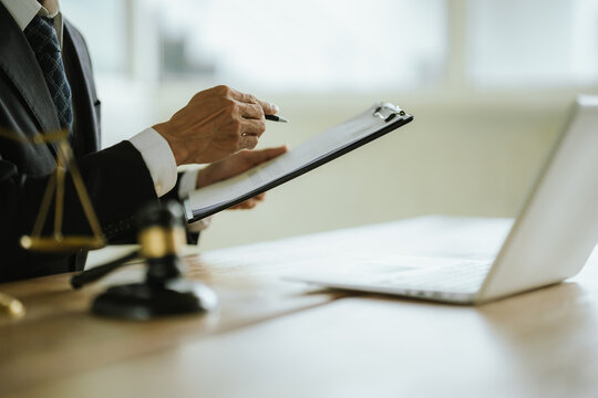 Lawyer reviewing legal documents with a laptop, gavel, and scales of justice, representing legal services, law practice, justice, and professional consultation.