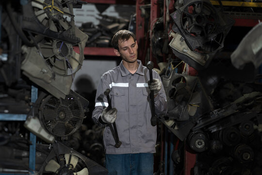 Automotive spare parts warehouse. Male warehouse worker inspecting spare parts in old auto parts warehouse. Male mechanic worker checking spare parts in workplace