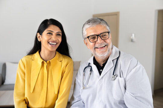 Portrait of positive female and male doctor smiling during conversation in medical office, representing healthcare services, trust in medicine, professional consultation, patient visit at hospital
