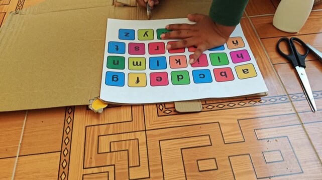 Child tracing lines on cardboard with pen using printed sheet as reference