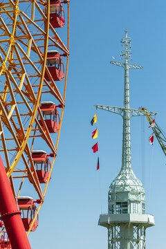 Mosaic Ferris Wheel and Historic Kobe Port Signal Tower Against Blue Sky in Japan, Waterfront Landmarks View
