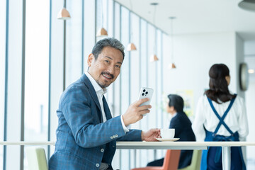 Fototapeta premium カフェでくつろぐミドルの男性 撮影協力：学校法人電波学園 東京電子専門学校