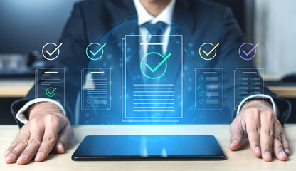 Fototapeta premium A businessman reviews documents on a tablet with digital checkmarks displayed, symbolizing efficiency and productivity in a modern office environment. Cyphers
