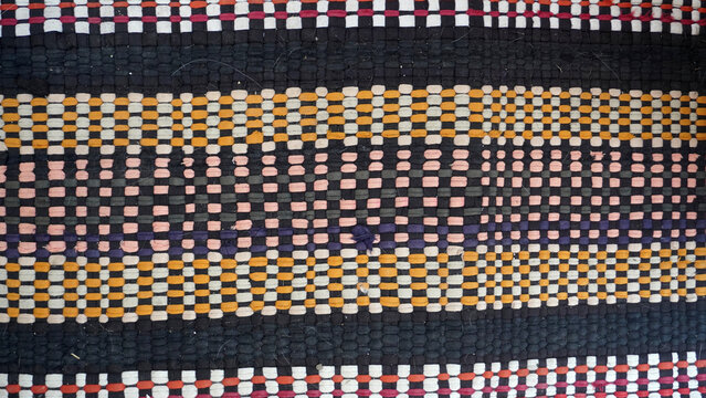 Traditional woven fabric texture with colorful geometric stripes.