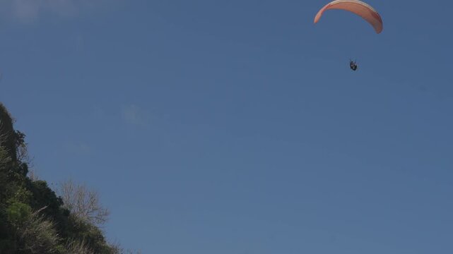 Pink paraglider soars against deep blue sky. Calm flight evokes freedom and serenity. Ideal for travel, adventure, or outdoor lifestyle themes. Sky's vastness emphasizes solitude and peace