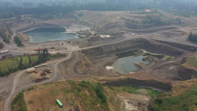 4K aerial drone footage of an active aggregate quarry in Sherwood, Oregon, USA under heavy wildfire smoke and hazy skies. Large open pit mine extracting rock and gravel amid poor air quality condition