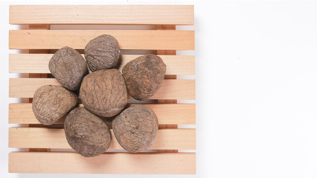 Dried keluwek pangium edule black nut on wooden tray isolated on white background
