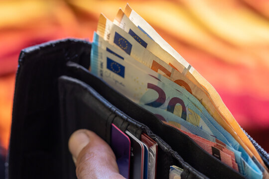 Black wallet filled with Euro banknotes and credit cards held in hand