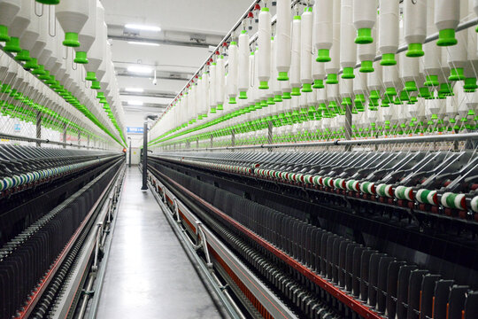 Modern textile mill interior with spinning machines and thread spools