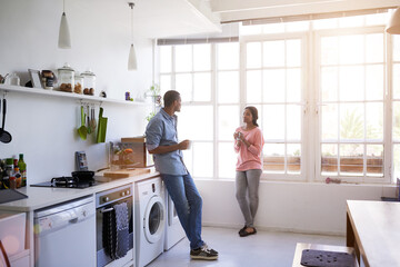 Obraz premium African couple, morning and coffee with relax in kitchen for bonding, relationship or holiday together. Home, happy man and woman with break for comfort, support and chat with conversation in house