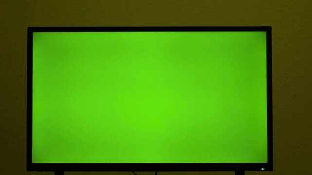 Computer monitor with chroma key green screen against textured wall