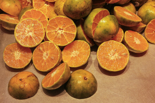 Fresh Thai Sai Nam Phueng mandarins are halved to reveal juicy orange flesh and green peels, creating a vibrant citrus concept for fresh juice, food and healthy lifestyle campaigns.