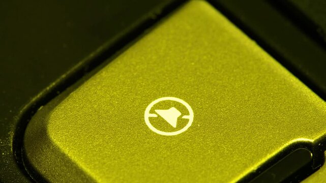 A finger presses volume down button on laptop keyboard in close up view