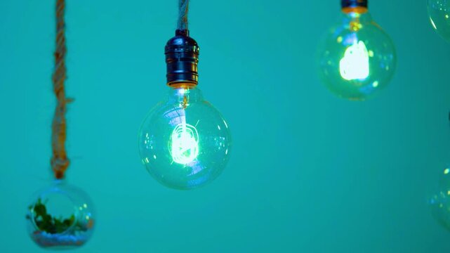 Vintage edison bulb glowing against teal background in slow motion