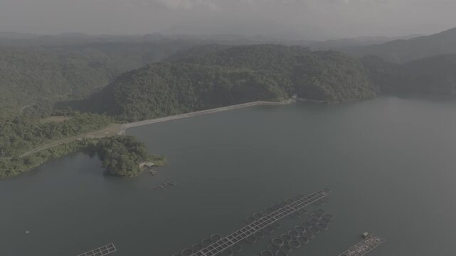 Drone flying over floating solar power plant surrounded by green mountains at Da Mi Lake, Binh Thuan, Lam Dong, Province. D log mode