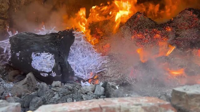 Shredded confidential documents burning in a brick furnace, paper strips curling into glowing embers and white ash as flames sweep over the pile