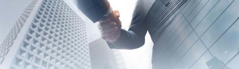 Obraz na płótnie Canvas Businessman hand shaking with partner, low angle view with modern business buildings background, Business cooperation, Investment and finance, Successful deal
