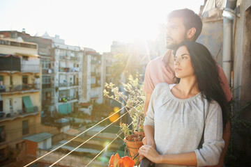 Obraz premium Thinking, couple and relax with love on balcony, peace and bonding together on calm morning. Flare, people and daydreaming on terrace for fresh air, home and sightseeing view for weekend break