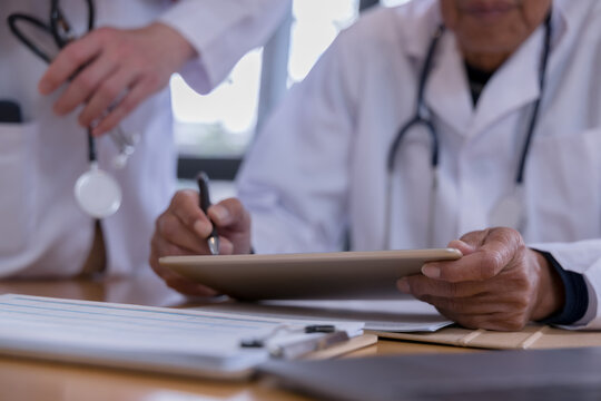 Medical team reviewing digital patient records with tablet and documents in a healthcare clinic. Doctors collaborating with health technology, electronic medical data, AI diagnostics modern clinical