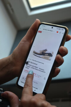 St- Amand Montrond - France - 5 August 2026 - Editorial detail of a woman's hands using a smartphone to add leopard print sneakers to a shopping cart on the Shein website, illustrating online fashion 