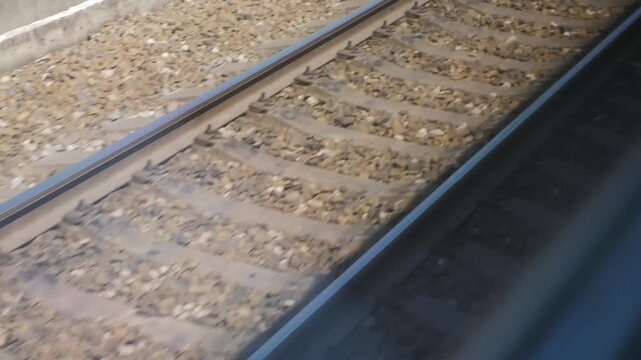 Close-up of moving railway tracks with gravel ballast and wooden sleepers from passing train. Motion blur creates dynamic travel atmosphere, fast transportation speed and journey concept 4k video
